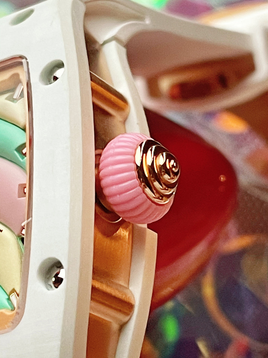 Close-up of a pink textured crown and gold-tone luxury timepiece case detail.