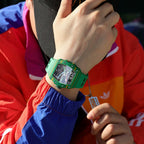 Green luxury chronograph watch with tonneau-shaped case and skeleton dial on a person's wrist.